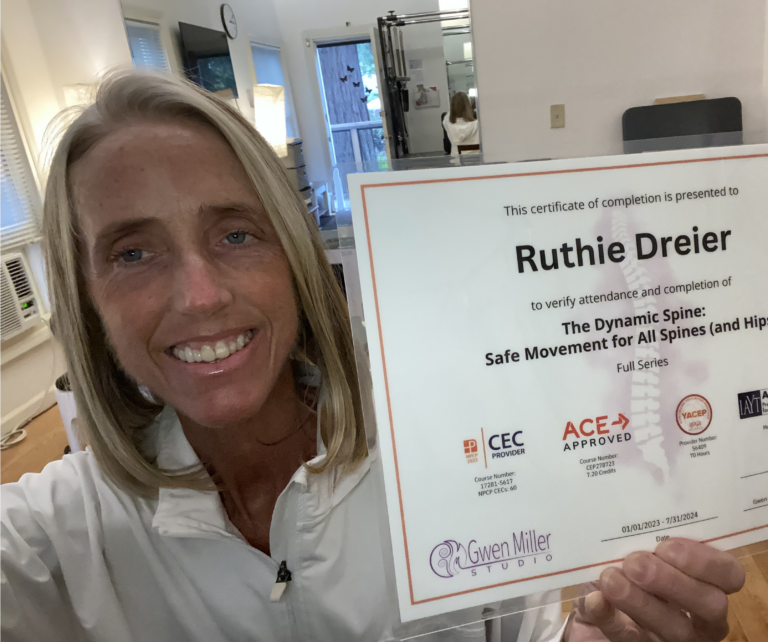 Smiling woman holds up a completion certificate in a bright room